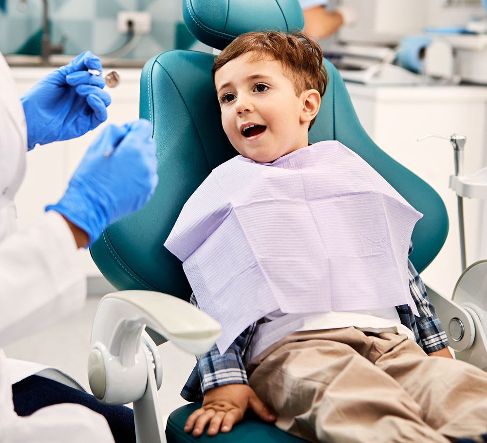small kid sitting in dental chair at dentist office